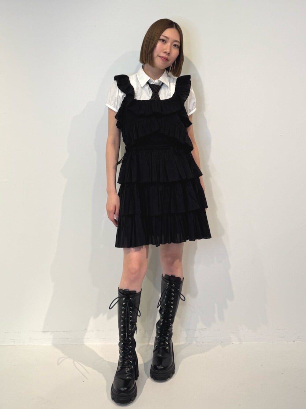 ブラック系のブーツ、ホワイト系のシャツ/ブラウス、ブラック系のネクタイを着用したレディースの春コーディネートの2枚目の写真