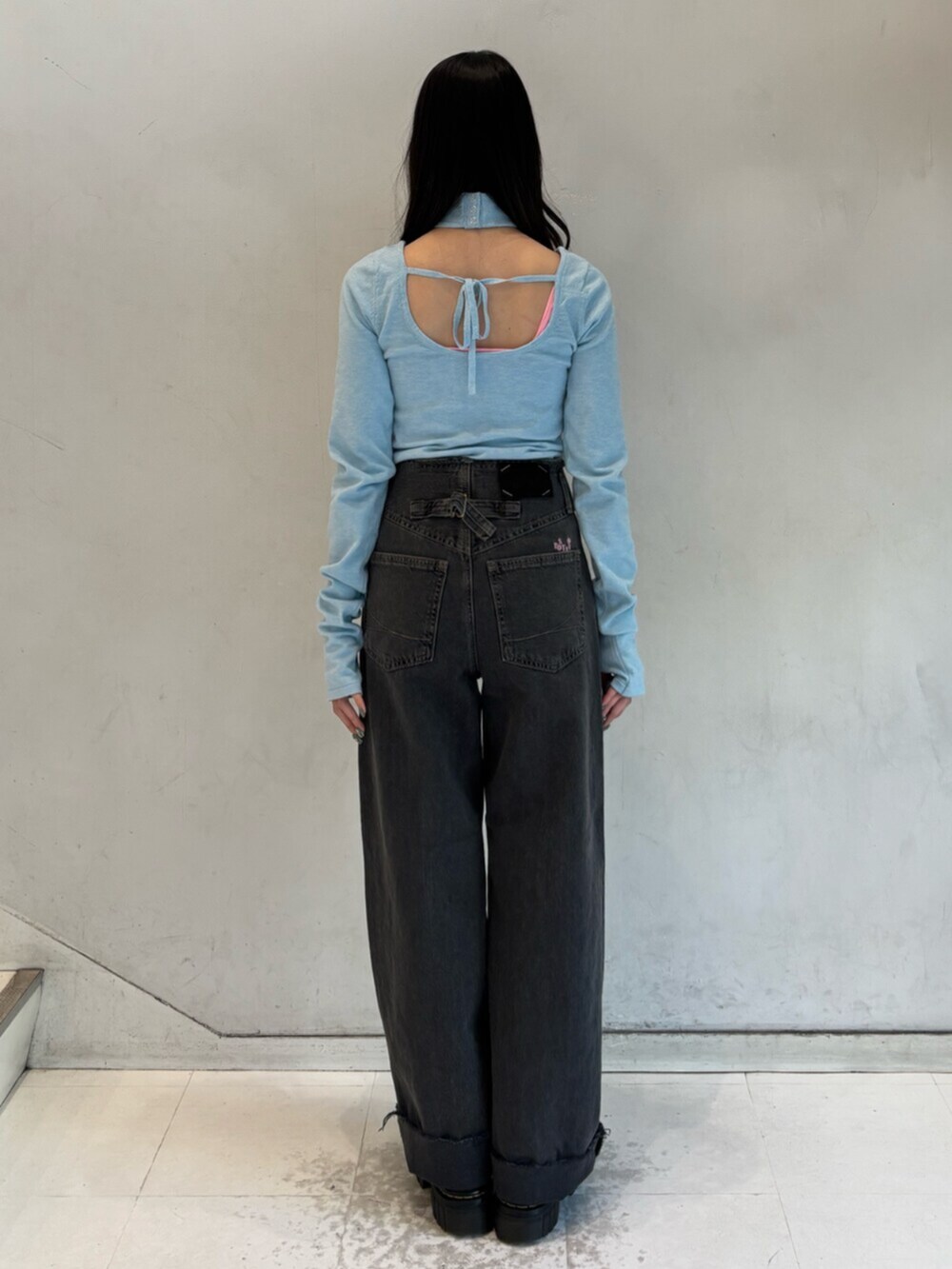 ブラック系のデニムパンツ、ブルー系のニット/セーター、シルバー系のメガネを着用したレディースの冬コーディネートの4枚目の写真