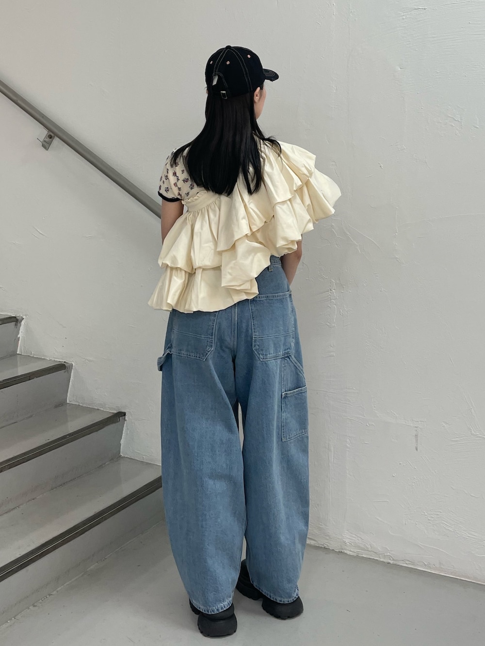 ブルー系のデニムパンツ、ホワイト系のスカート、ホワイト系のTシャツ/カットソーを着用したレディースの春コーディネートの3枚目の写真