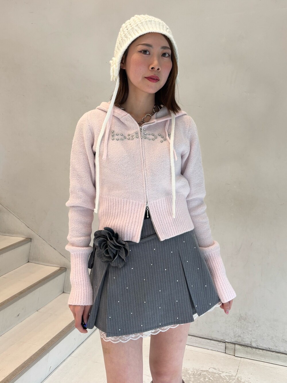 ピンク系のパーカー、グレー系のスカート、ホワイト系のブーツを着用したレディースの冬コーディネートの6枚目の写真