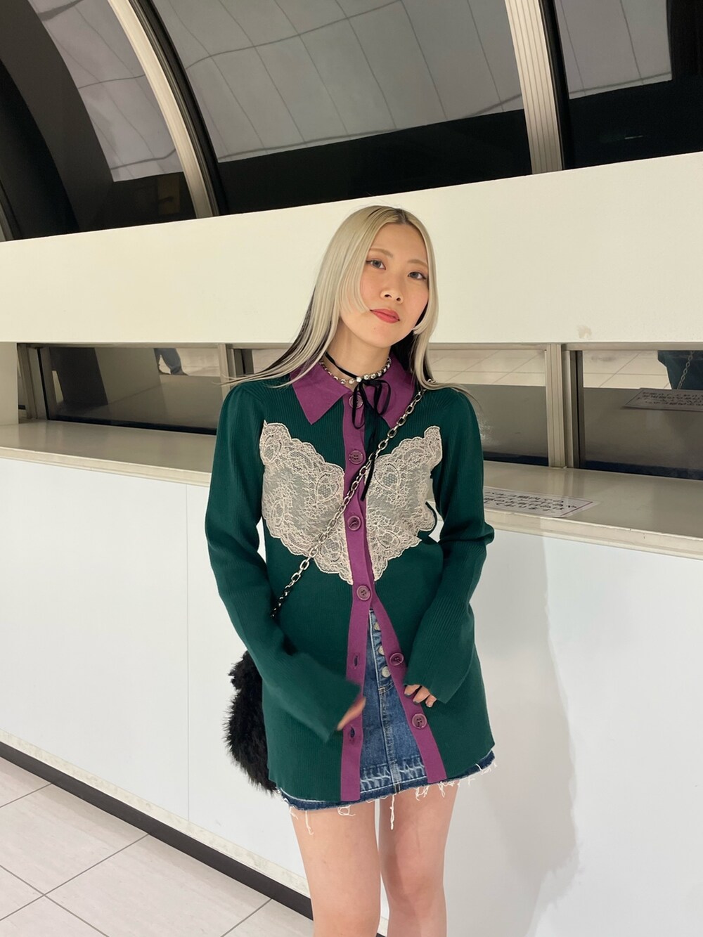 グリーン系のカーディガン/ボレロ、ブルー系のデニムパンツ、ブラック系のハンドバッグを着用したレディースの冬コーディネートの5枚目の写真