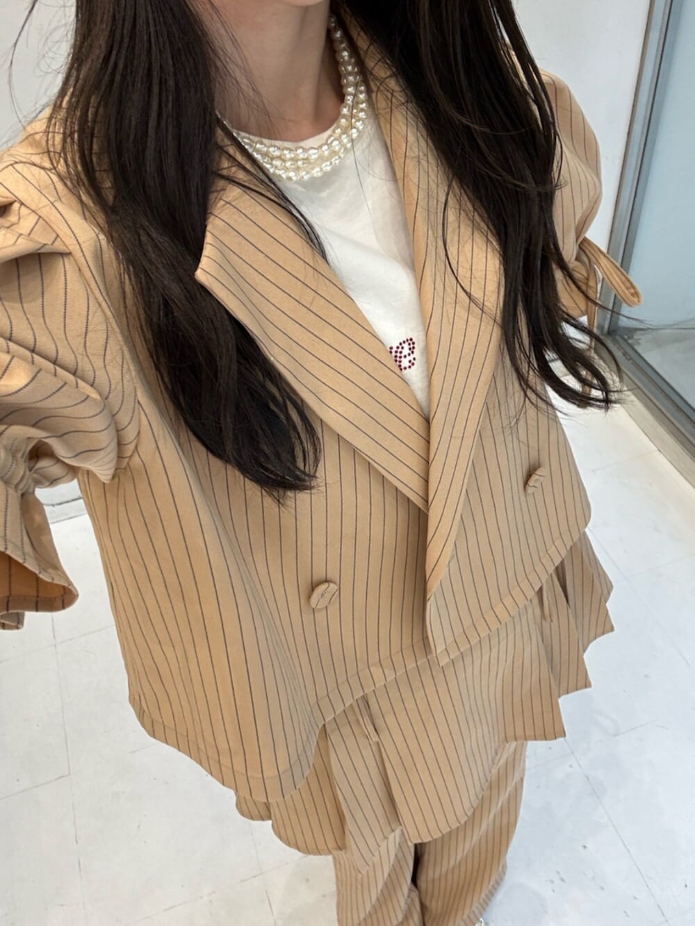 ベージュ系のテーラードジャケット、ベージュ系のその他パンツ、ベージュ系のスカートを着用したレディースの冬コーディネートの9枚目の写真