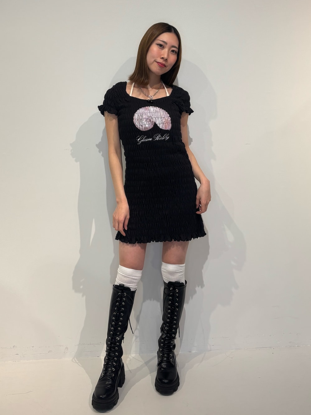 ブラック系のワンピース、ブラック系のブーツ、ホワイト系のキャミソールを着用したレディースの冬コーディネートの2枚目の写真