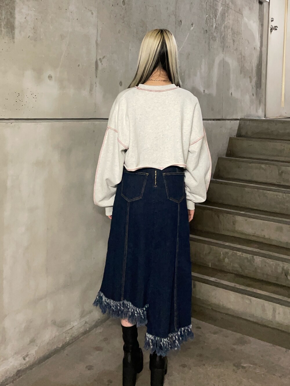 グレー系のスウェット、ブルー系のジャンパースカート、ブラック系のブーツを着用したレディースの冬コーディネートの3枚目の写真