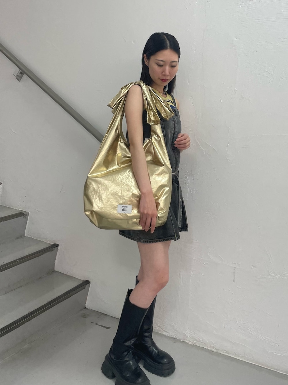 ブラック系のワンピース、イエロー系のタンクトップ、ゴールド系のトートバッグを着用したレディースの夏コーディネートの3枚目の写真