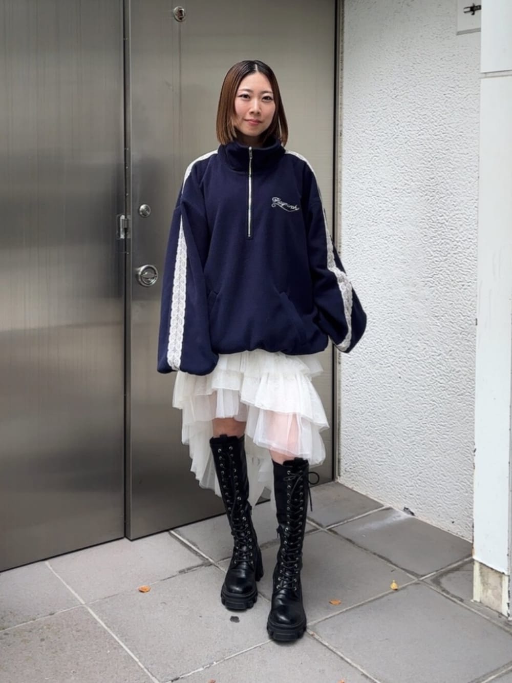 ブラック系のブーツ、ブルー系のTシャツ/カットソー、ホワイト系のスカートを着用したレディースの秋コーディネートの2枚目の写真