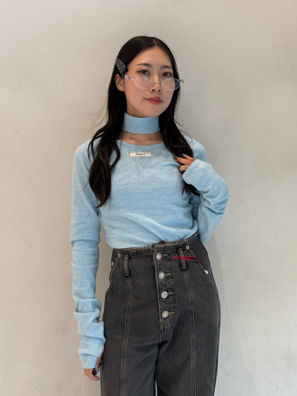 ブラック系のデニムパンツ、ブルー系のニット/セーター、シルバー系のメガネを着用したレディースの冬コーディネートの6枚目の写真