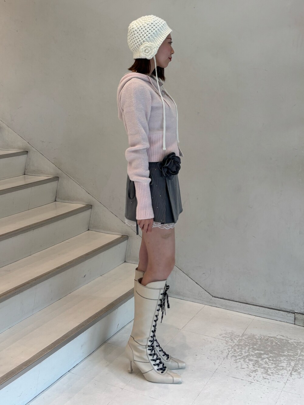 ピンク系のパーカー、グレー系のスカート、ホワイト系のブーツを着用したレディースの冬コーディネートの3枚目の写真