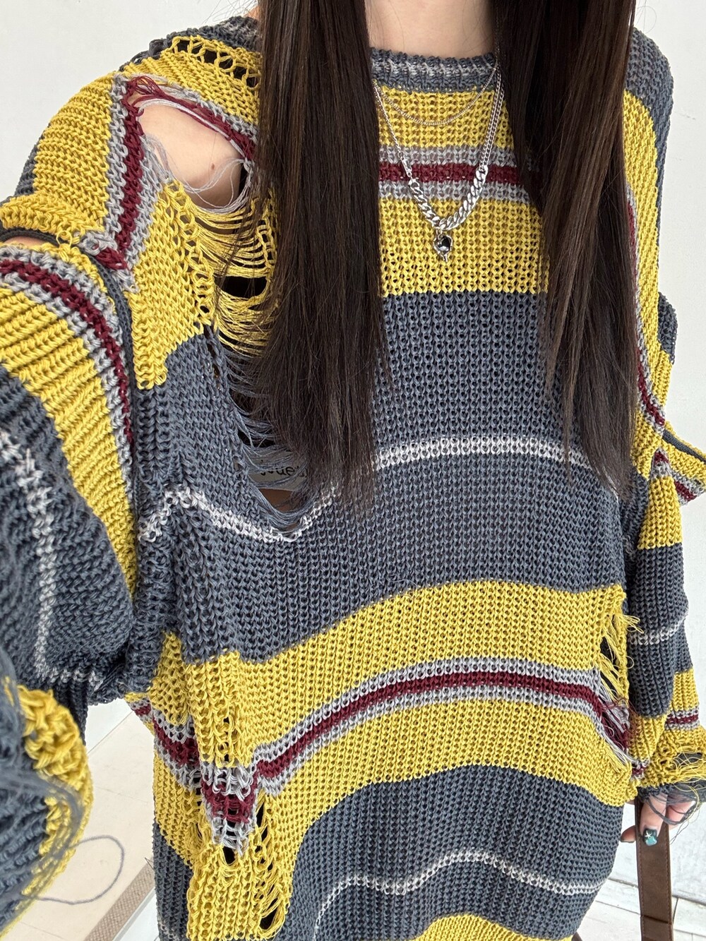 ブラウン系のハンドバッグ、ブラック系のニット/セーター、ブラック系のスニーカーを着用したレディースの春コーディネートの9枚目の写真
