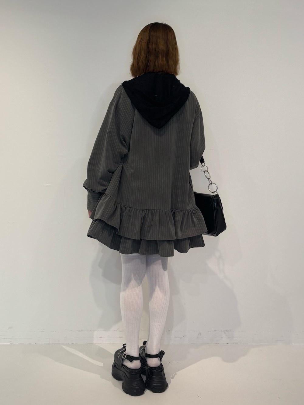 グレー系のワンピース、ブラック系のスカート、ブラック系のパーカーを着用したレディースの春コーディネートの4枚目の写真