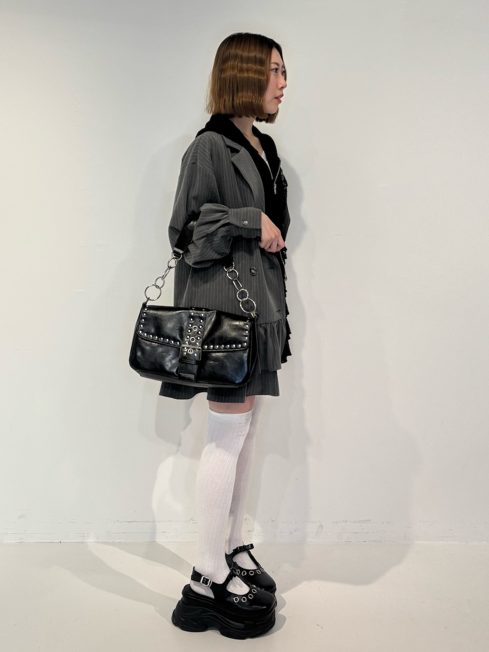 グレー系のワンピース、ブラック系のスカート、ブラック系のパーカーを着用したレディースの春コーディネートの3枚目の写真