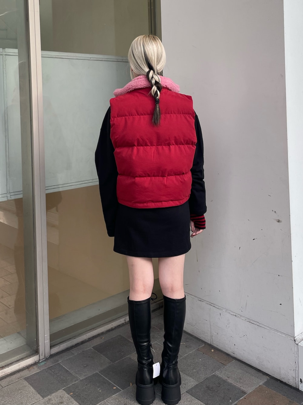 ブラック系のシャツワンピース、レッド系のダウンベスト、ブラック系のブーツを着用したレディースの秋コーディネートの4枚目の写真