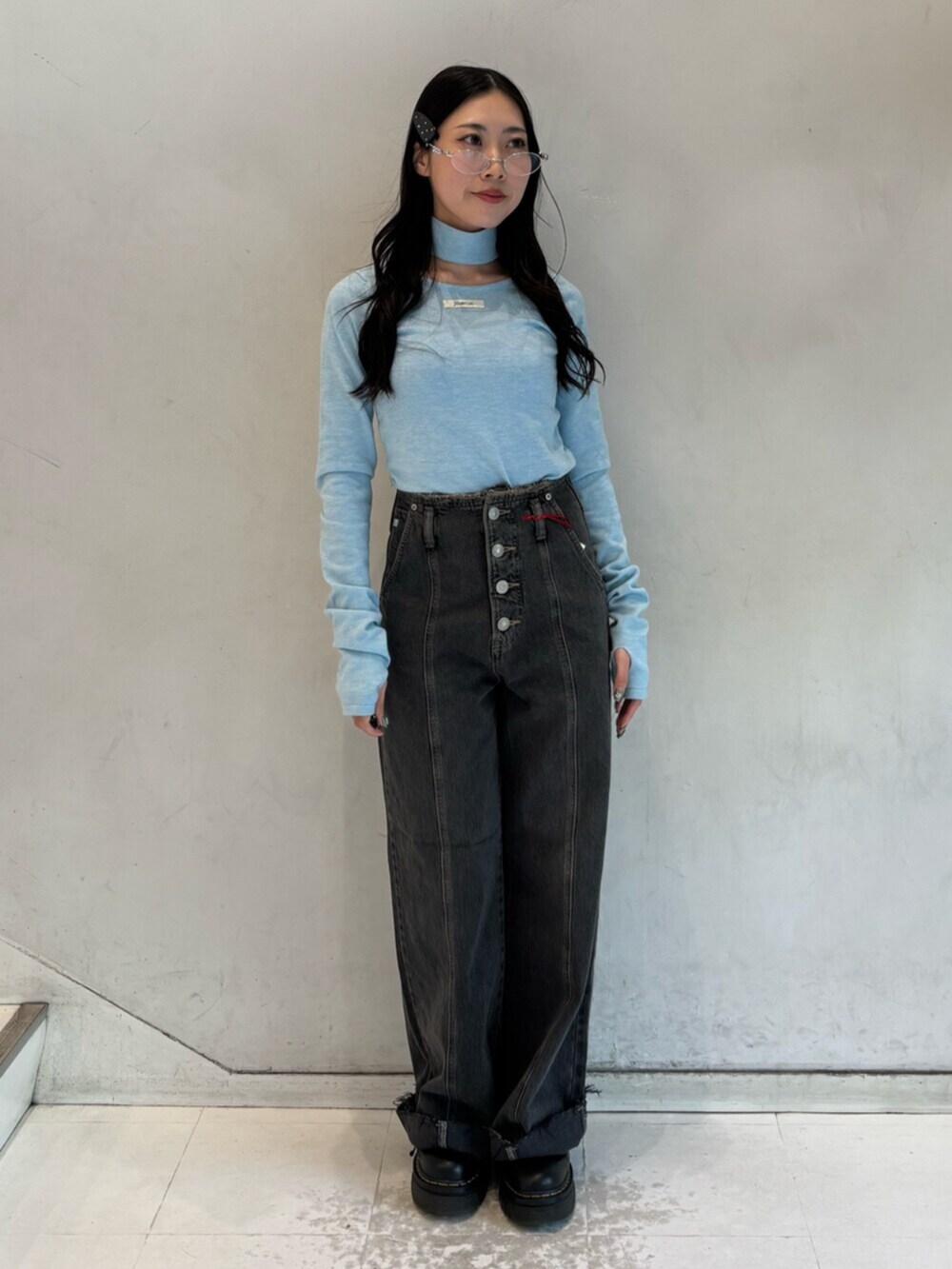 ブラック系のデニムパンツ、ブルー系のニット/セーター、シルバー系のメガネを着用したレディースの冬コーディネートの2枚目の写真