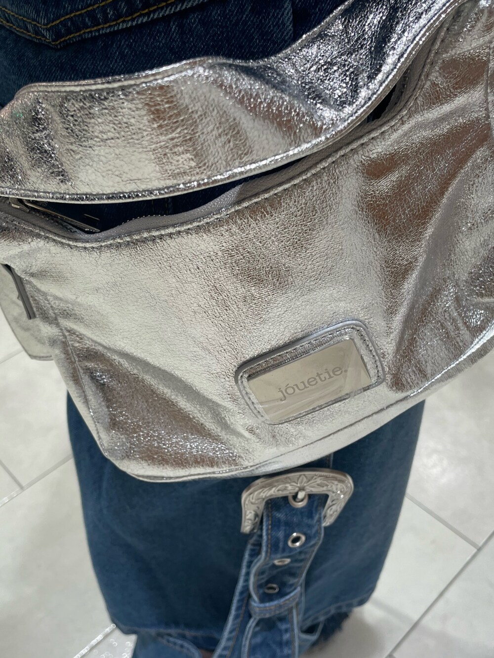 ブルー系のデニムパンツ、ブラック系のカーディガン/ボレロ、シルバー系のハンドバッグを着用したレディースの秋コーディネートの10枚目の写真