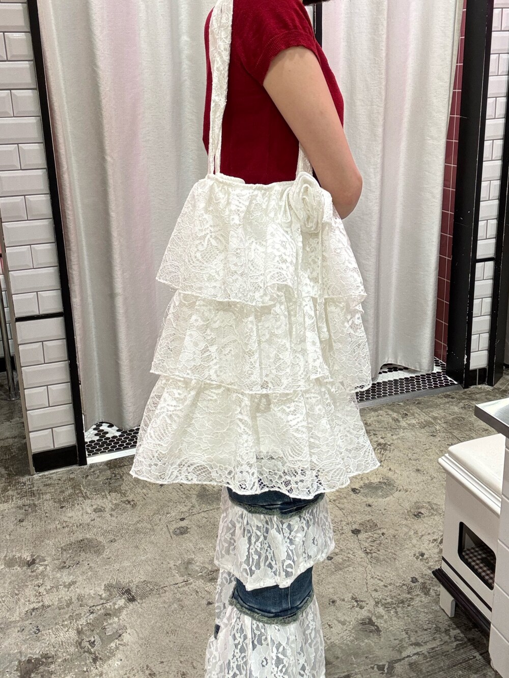 ブルー系のデニムパンツ、ホワイト系のトートバッグ、レッド系のニット/セーターを着用したレディースの春コーディネートの9枚目の写真