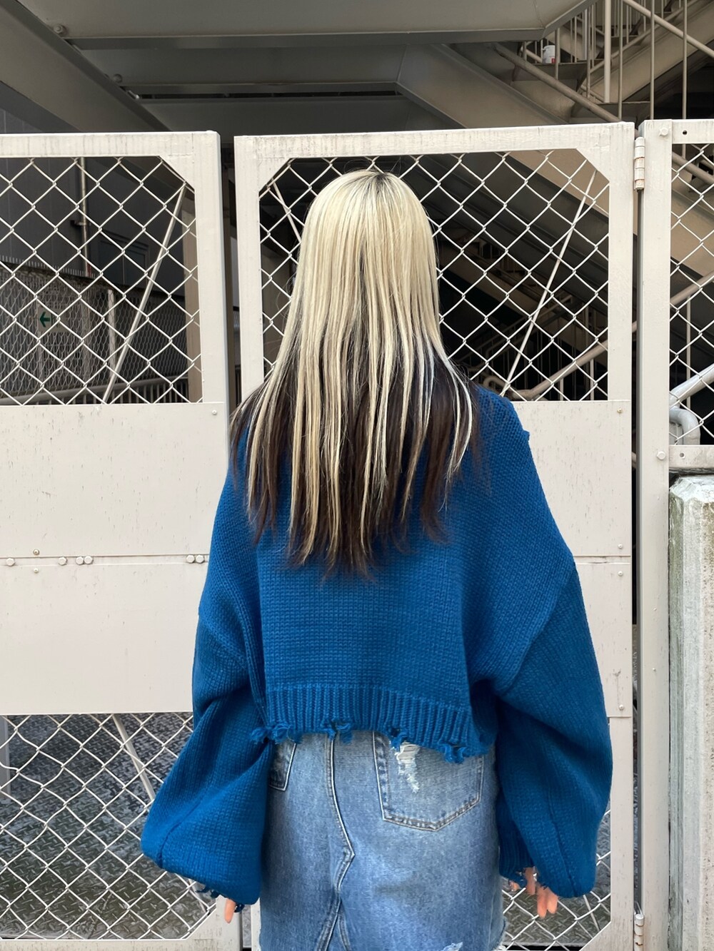 ブルー系のニット/セーター、ブルー系のデニムスカート、ブラック系のブーツを着用したレディースの冬コーディネートの6枚目の写真