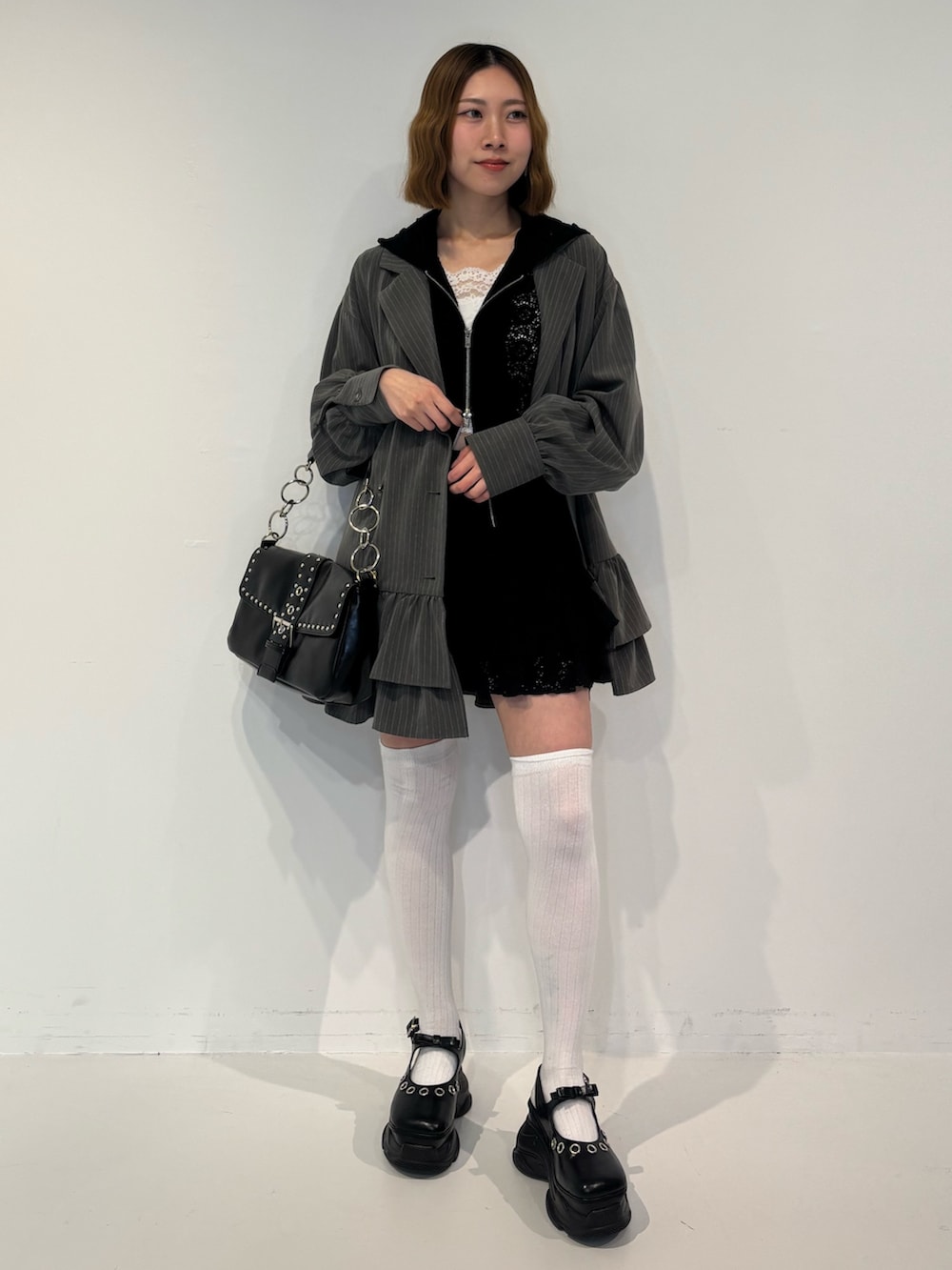 グレー系のワンピース、ブラック系のスカート、ブラック系のパーカーを着用したレディースの春コーディネートの2枚目の写真