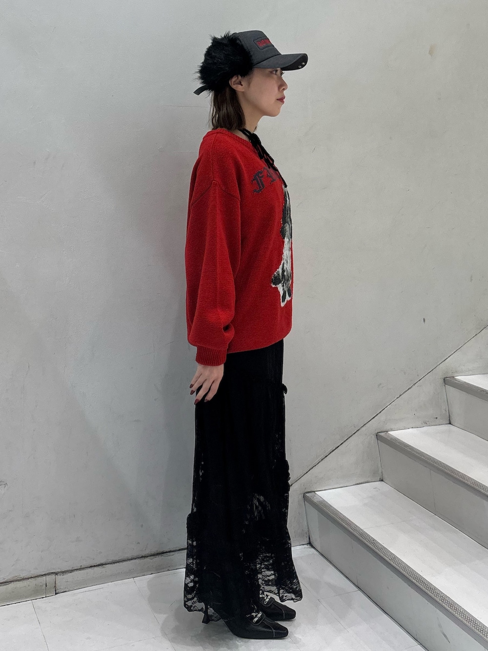 レッド系のニット/セーター、ブラック系のワンピース、ブラック系のブーツを着用したレディースの冬コーディネートの3枚目の写真