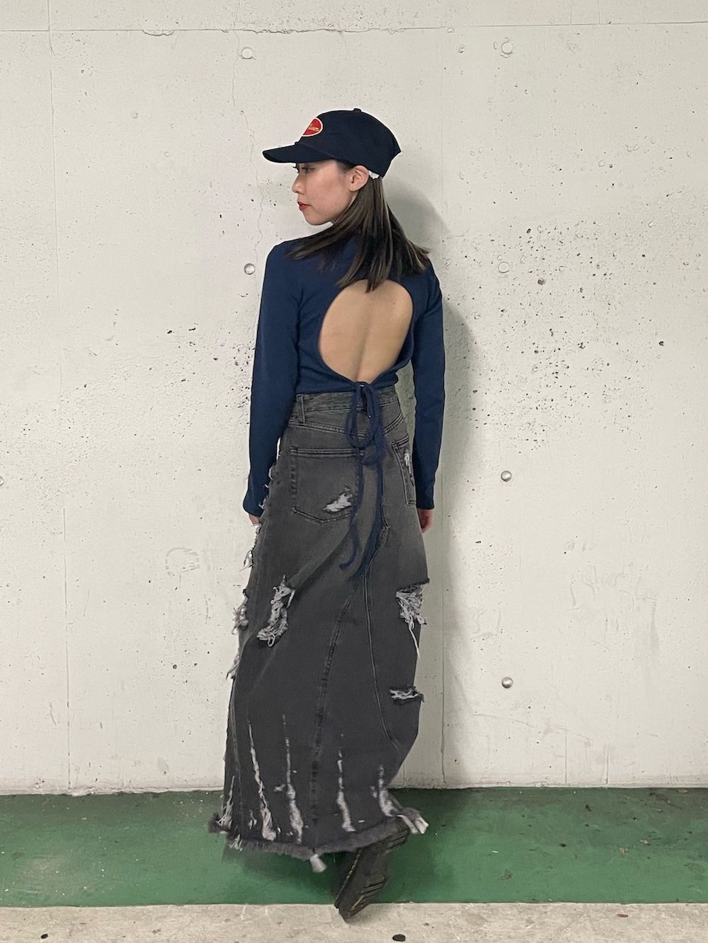 ブラック系のデニムスカート、ブラック系のTシャツ/カットソー、ブルー系のキャップを着用したレディースの冬コーディネートの2枚目の写真