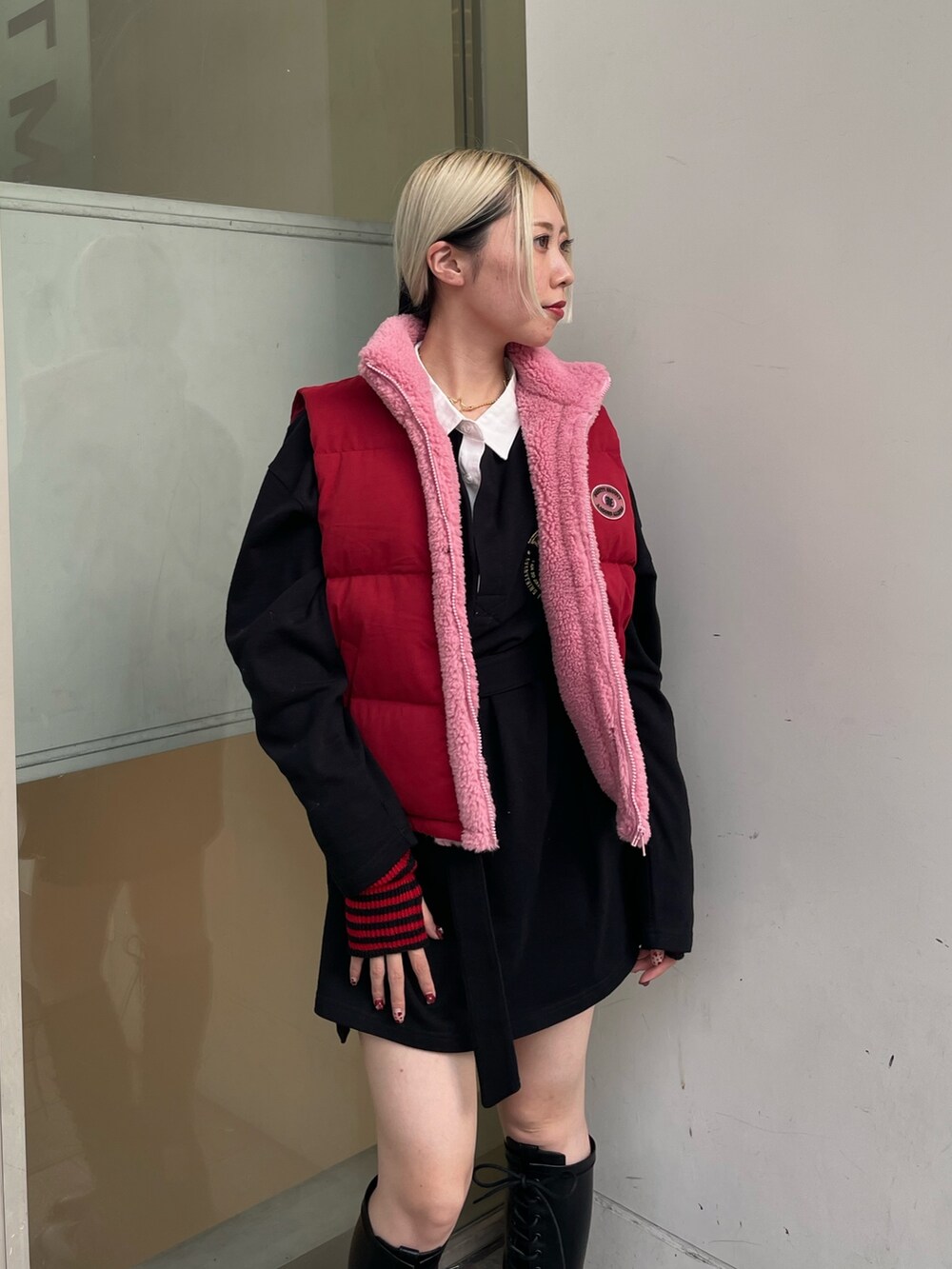 ブラック系のシャツワンピース、レッド系のダウンベスト、ブラック系のブーツを着用したレディースの秋コーディネートの5枚目の写真