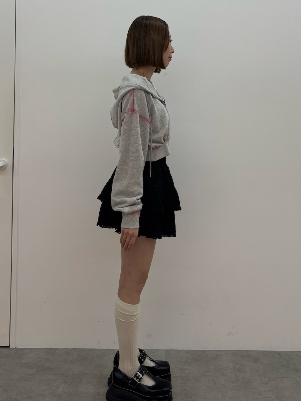 グレー系のパーカー、ブラック系のローファー、シルバー系のネックレスを着用したレディースの春コーディネートの3枚目の写真