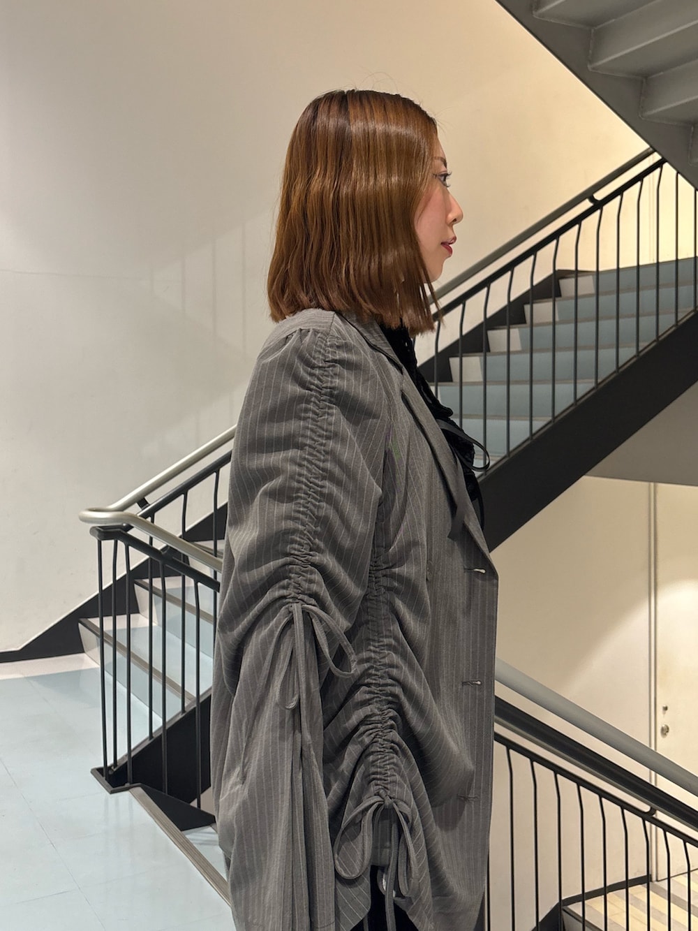 ブラック系のワンピース、グレー系のテーラードジャケット、ブラウン系のブーツを着用したレディースの冬コーディネートの7枚目の写真