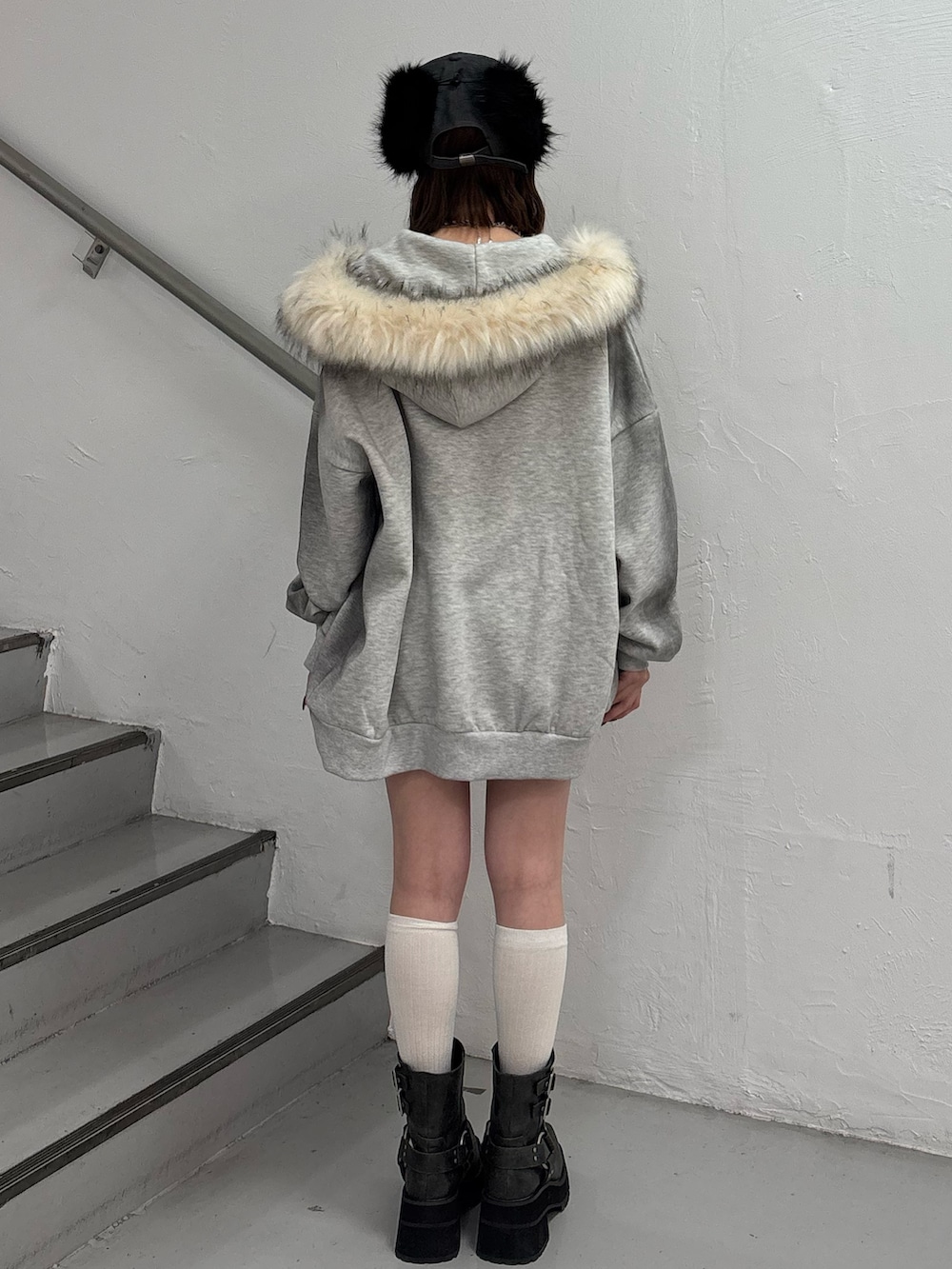 ブラック系のスカート、グレー系のパーカー、ブラック系のブーツを着用したレディースの冬コーディネートの4枚目の写真