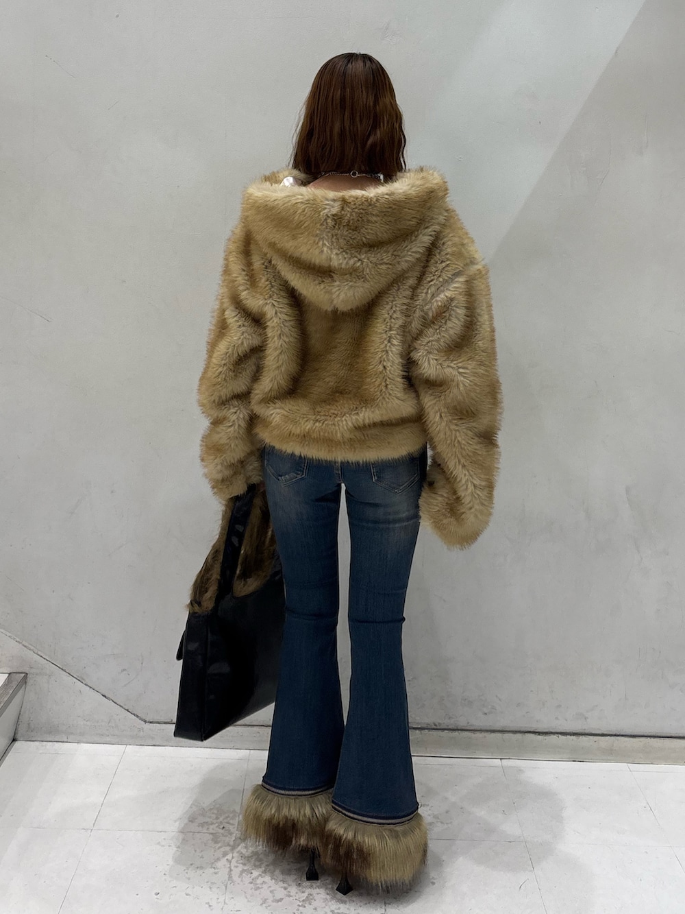 ブルー系のデニムパンツ、ブラック系のハンドバッグ、ブラック系のパンプスを着用したレディースの秋コーディネートの4枚目の写真