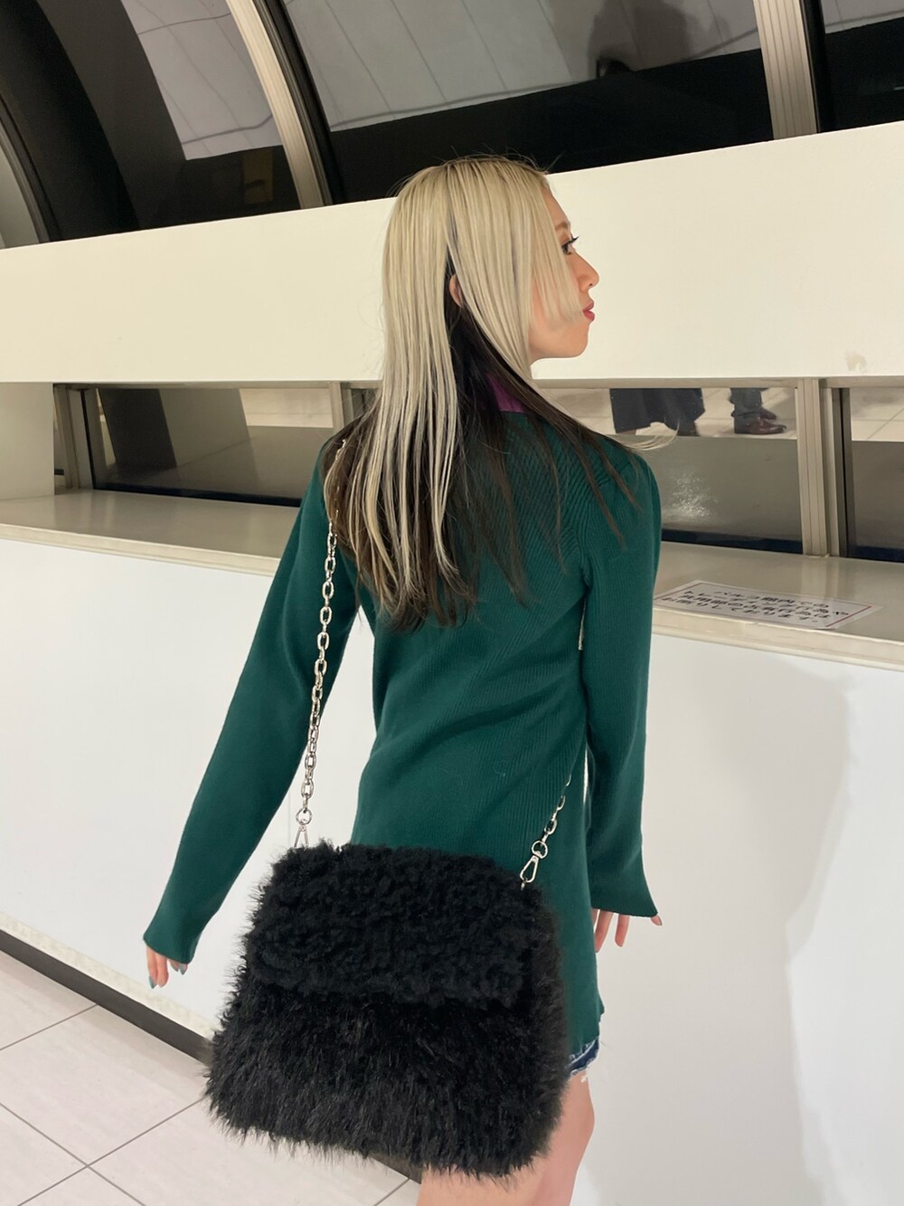 グリーン系のカーディガン/ボレロ、ブルー系のデニムパンツ、ブラック系のハンドバッグを着用したレディースの冬コーディネートの7枚目の写真