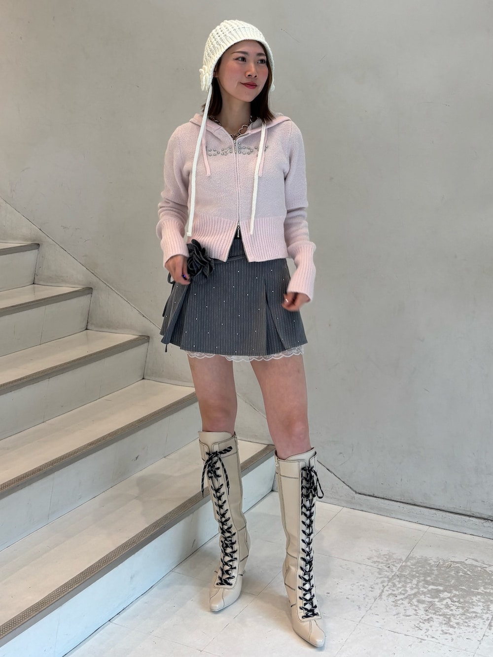 ピンク系のパーカー、グレー系のスカート、ホワイト系のブーツを着用したレディースの冬コーディネートの2枚目の写真