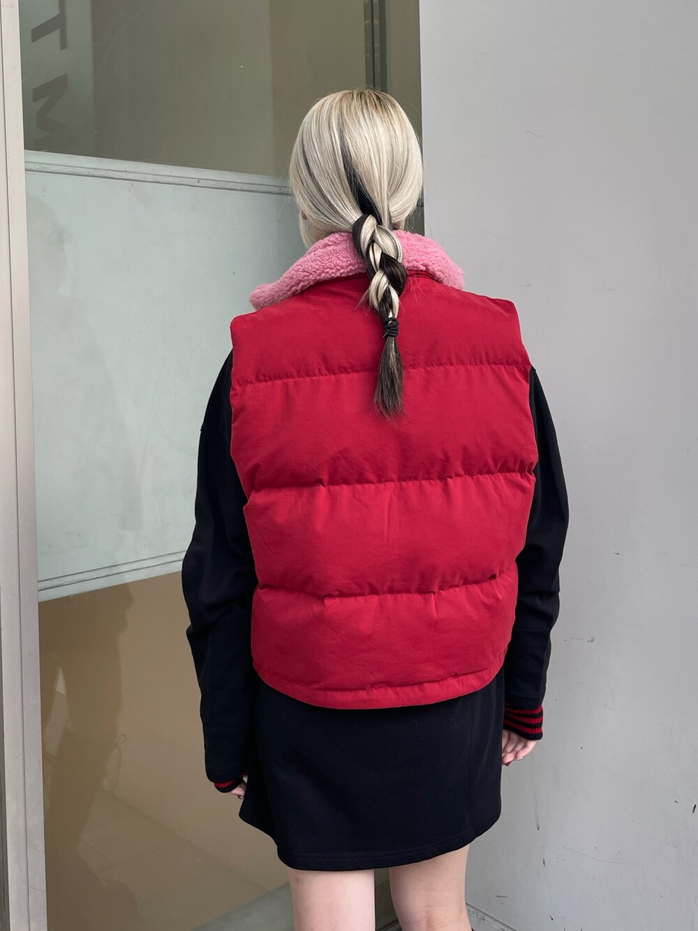 ブラック系のシャツワンピース、レッド系のダウンベスト、ブラック系のブーツを着用したレディースの秋コーディネートの7枚目の写真