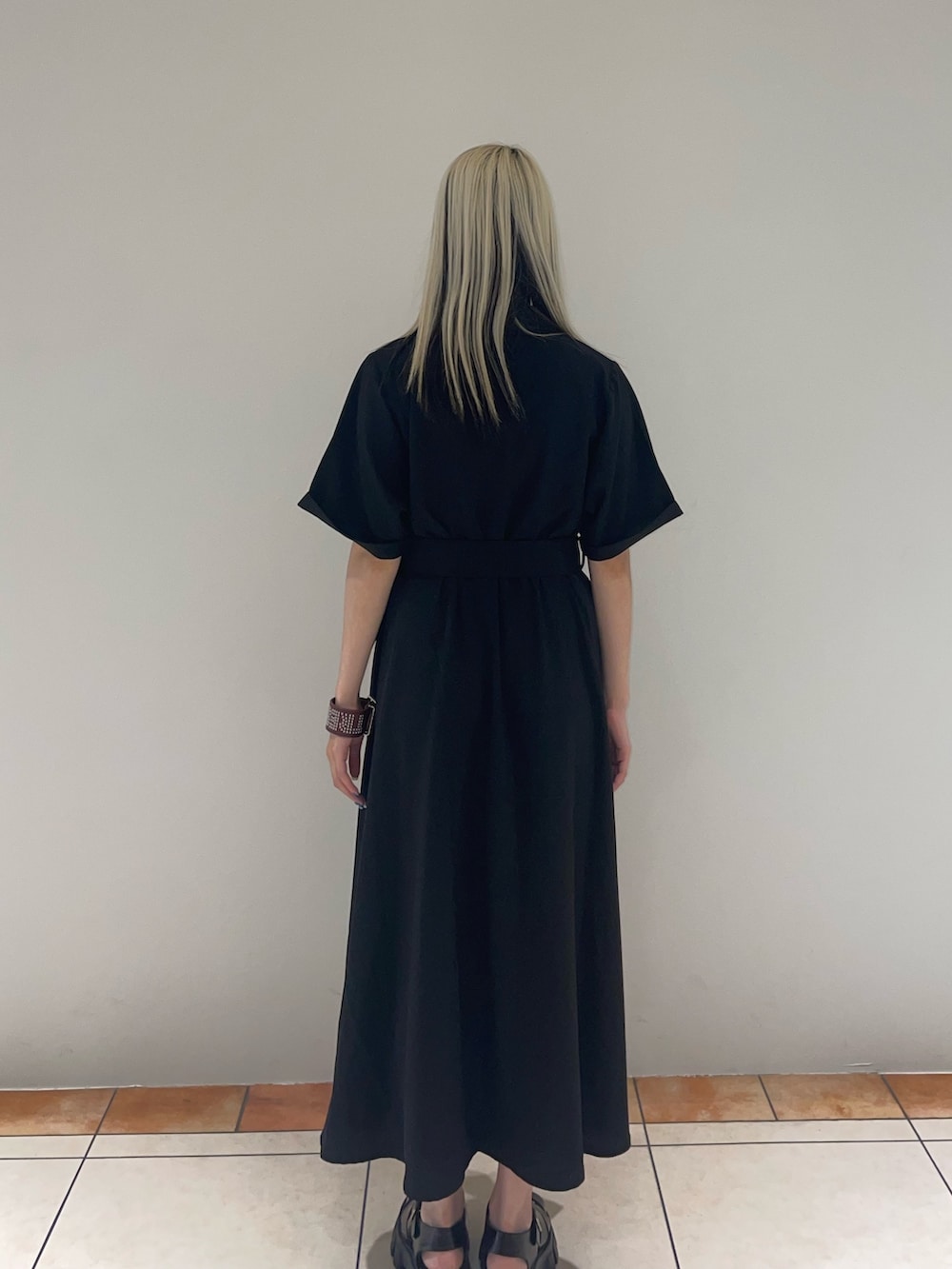 ブラック系のワンピース、ブラック系のサンダル、レッド系のブレスレットを着用したレディースの夏コーディネートの4枚目の写真