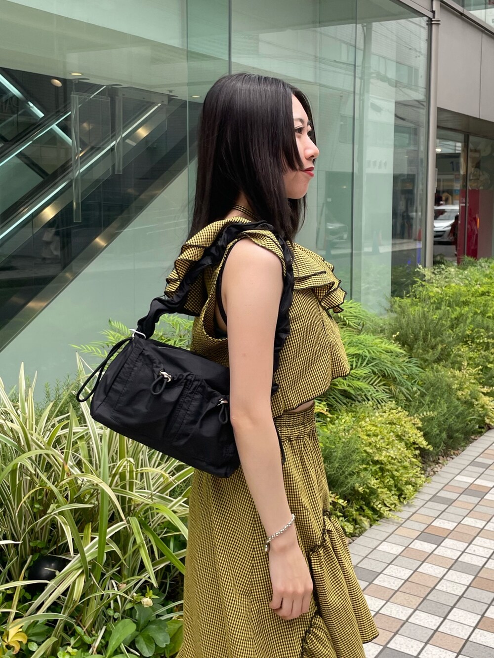 イエロー系のスカート、イエロー系のシャツ/ブラウス、ブラック系のショルダーバッグを着用したレディースの夏コーディネートの4枚目の写真