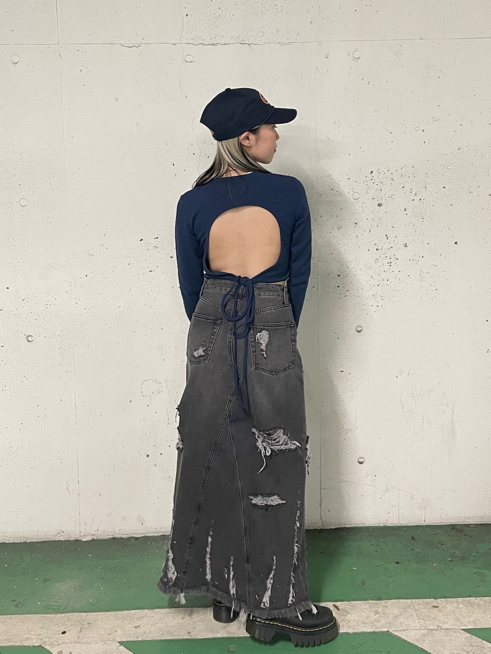 ブラック系のデニムスカート、ブラック系のTシャツ/カットソー、ブルー系のキャップを着用したレディースの冬コーディネートの4枚目の写真