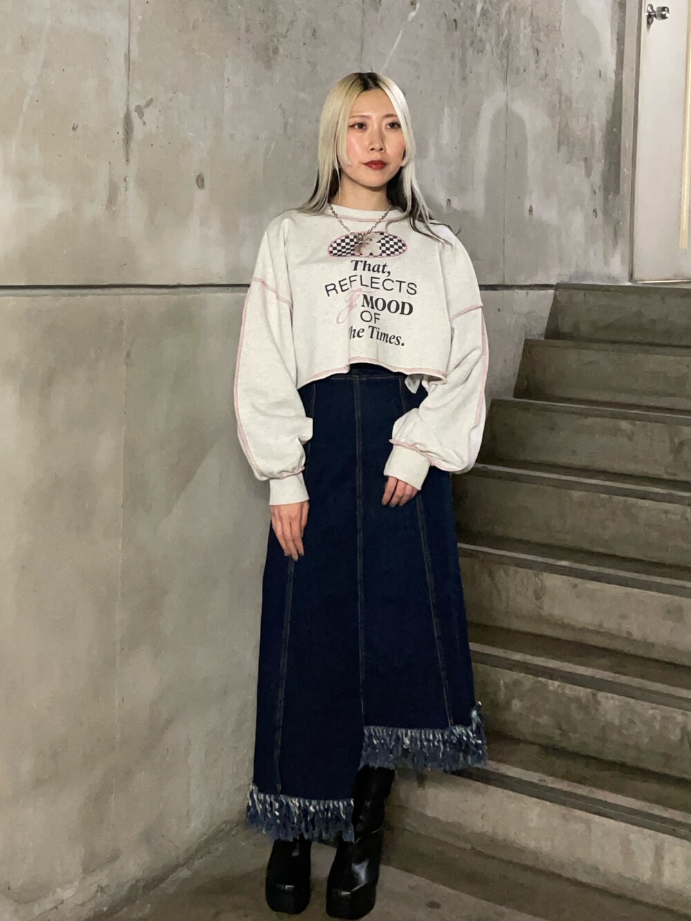 グレー系のスウェット、ブルー系のジャンパースカート、ブラック系のブーツを着用したレディースの冬コーディネートの2枚目の写真