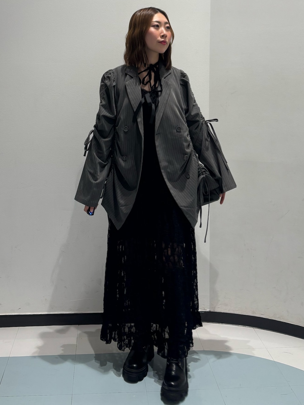 ブラック系のワンピース、グレー系のテーラードジャケット、ブラウン系のブーツを着用したレディースの冬コーディネートの2枚目の写真