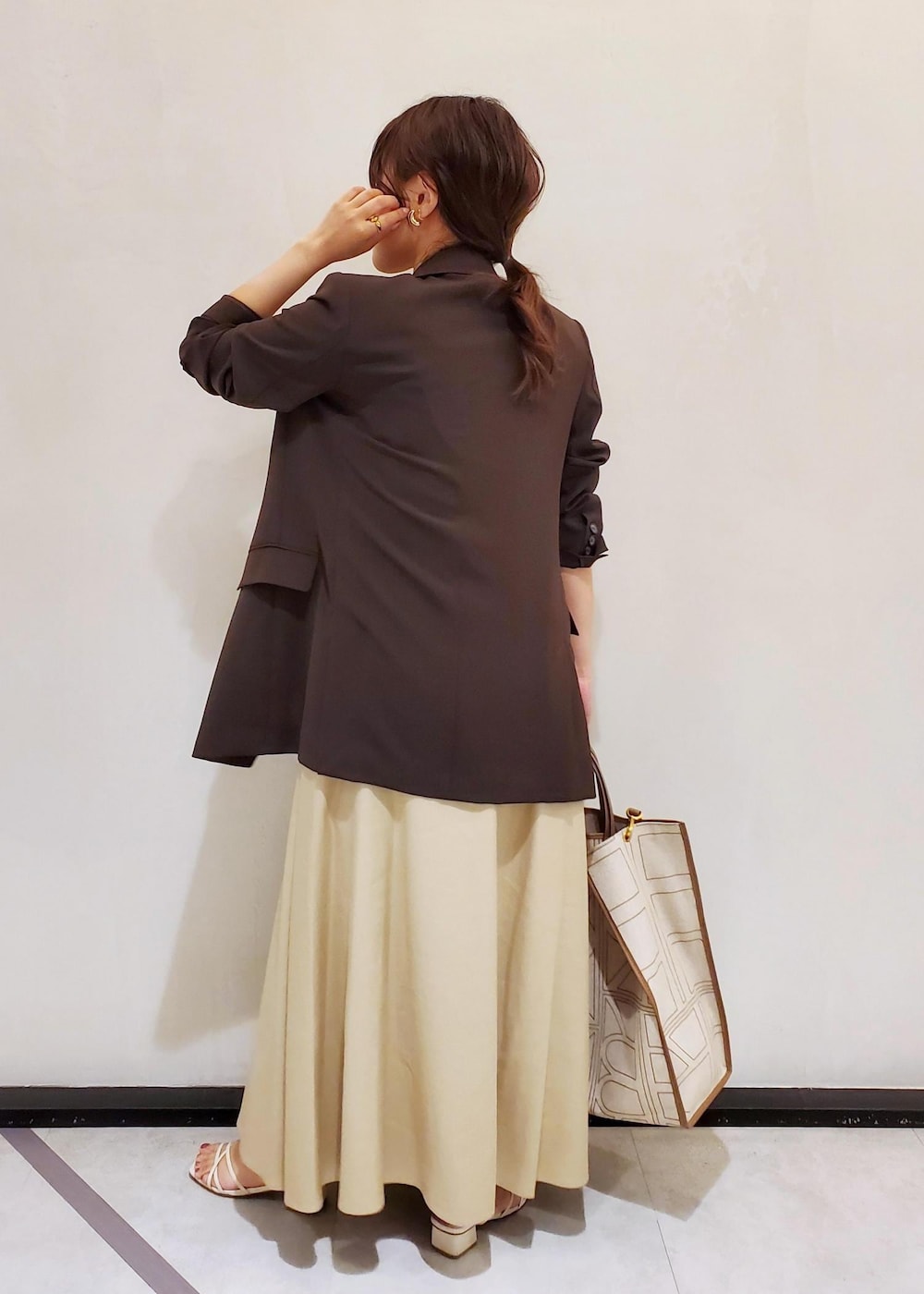 ブラウン系のテーラードジャケット、ベージュ系のワンピース、ゴールド系のネックレスを着用したレディースの春コーディネートの3枚目の写真