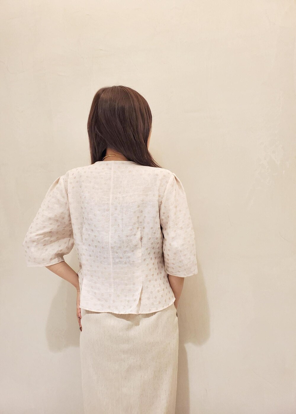 ブラック系のハンドバッグ、ブラック系のパンプス、ホワイト系のスカートを着用したレディースの夏コーディネートの5枚目の写真