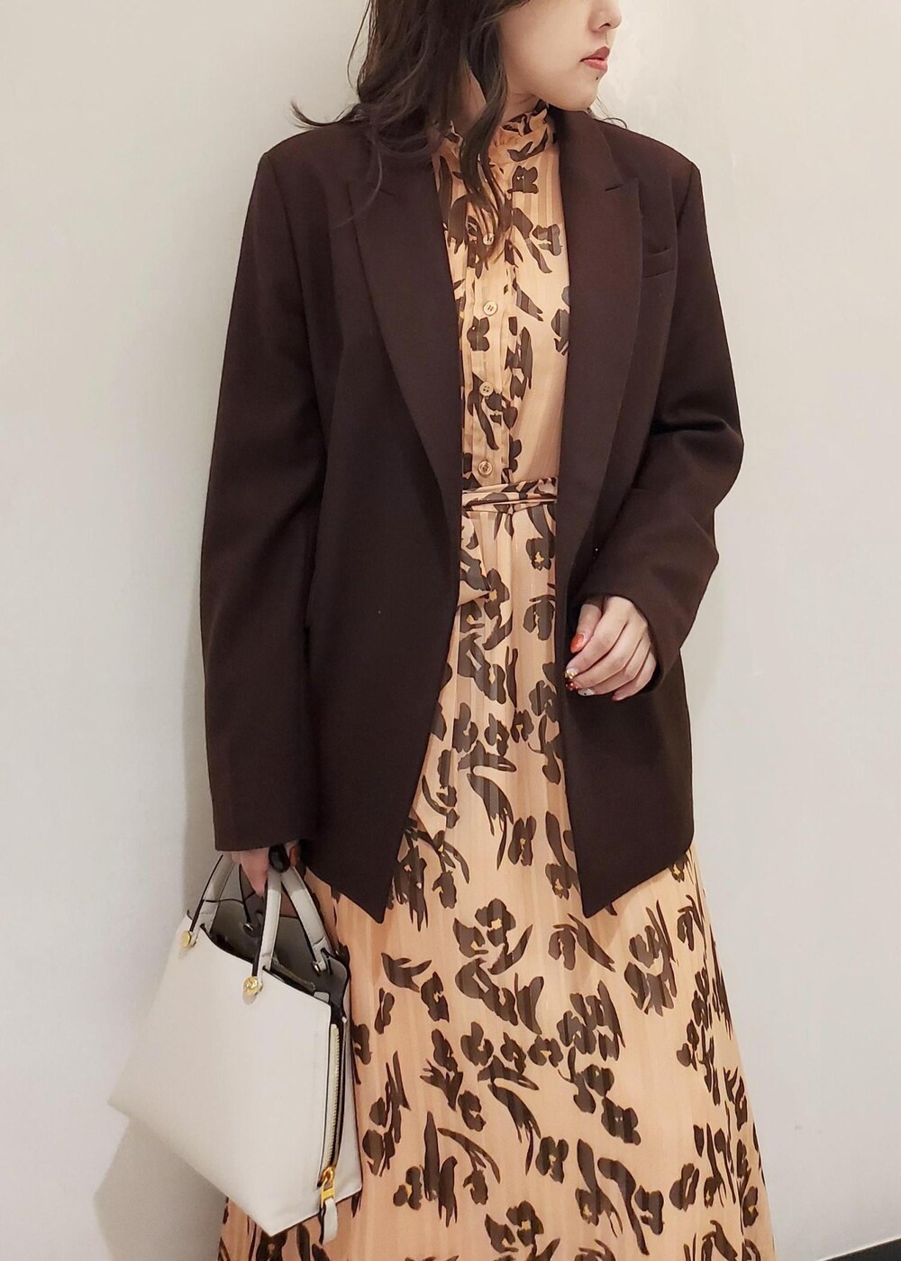 グレー系のハンドバッグ、ブラウン系のテーラードジャケット、オレンジ系のワンピースを着用したレディースの冬コーディネートの4枚目の写真