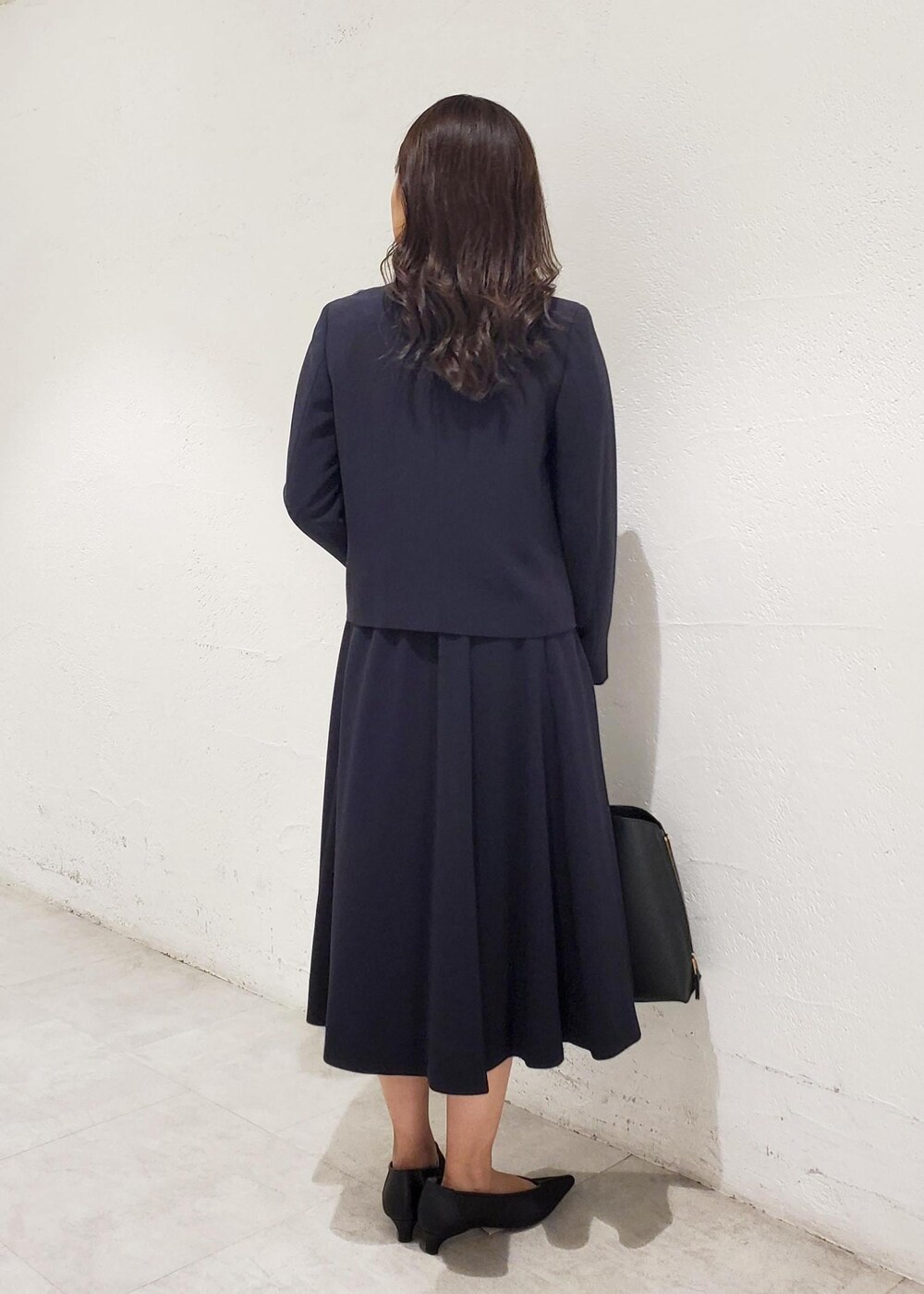 ブラック系のトートバッグ、ブラック系のパンプス、ブルー系のシャツ/ブラウスを着用したレディースの秋コーディネートの3枚目の写真