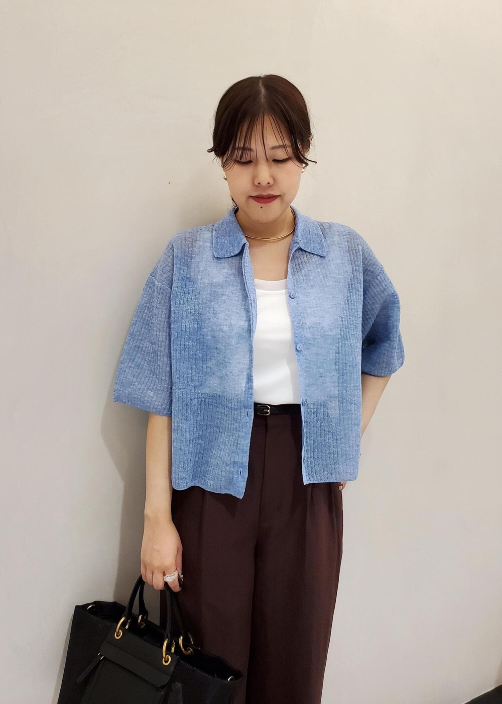 ブラック系のハンドバッグ、ブルー系のカーディガン/ボレロ、ホワイト系のタンクトップを着用したレディースの夏コーディネートの4枚目の写真