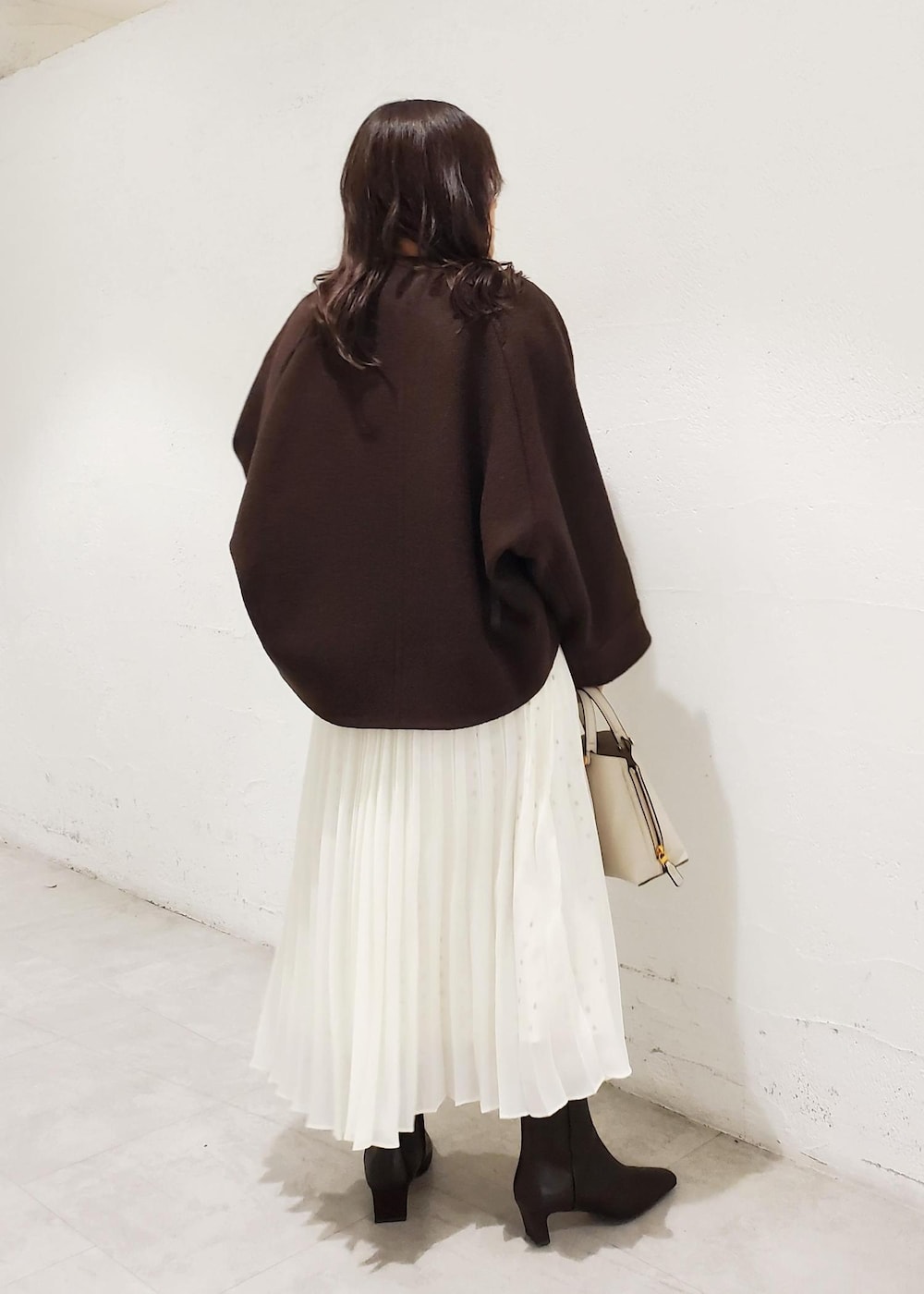 グレー系のハンドバッグ、ブラウン系のブーツ、ブラウン系のブルゾンを着用したレディースの秋コーディネートの3枚目の写真