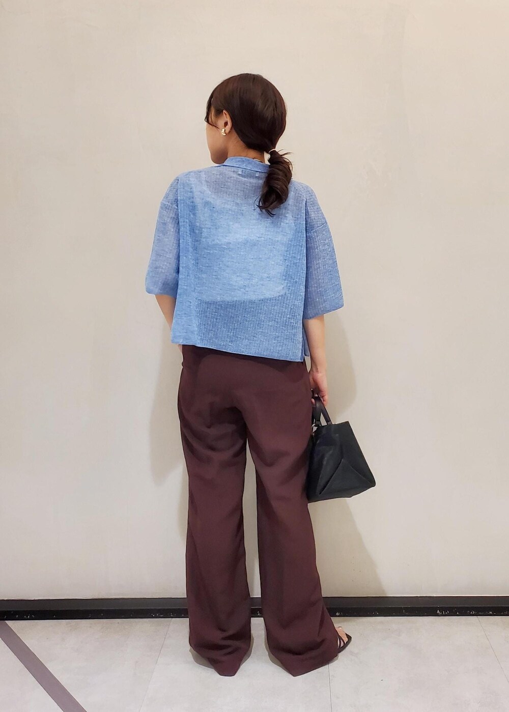 ブラック系のハンドバッグ、ブルー系のカーディガン/ボレロ、ホワイト系のタンクトップを着用したレディースの夏コーディネートの3枚目の写真