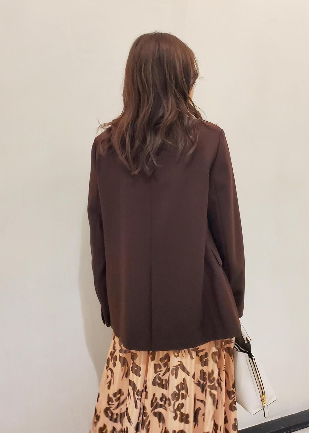 グレー系のハンドバッグ、ブラウン系のテーラードジャケット、オレンジ系のワンピースを着用したレディースの冬コーディネートの6枚目の写真