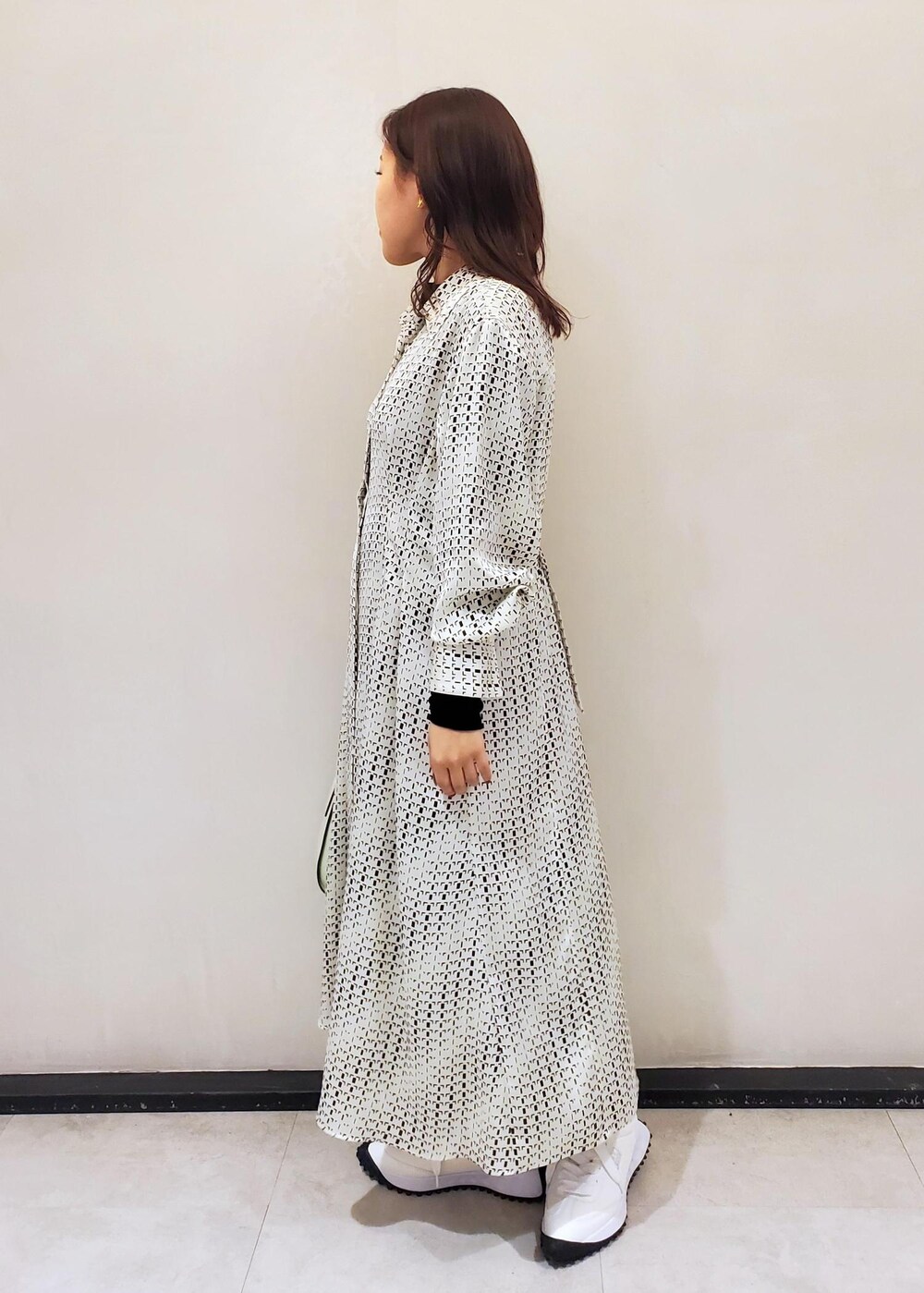 グリーン系のハンドバッグ、ホワイト系のスニーカー、ホワイト系のワンピースを着用したレディースの冬コーディネートの2枚目の写真