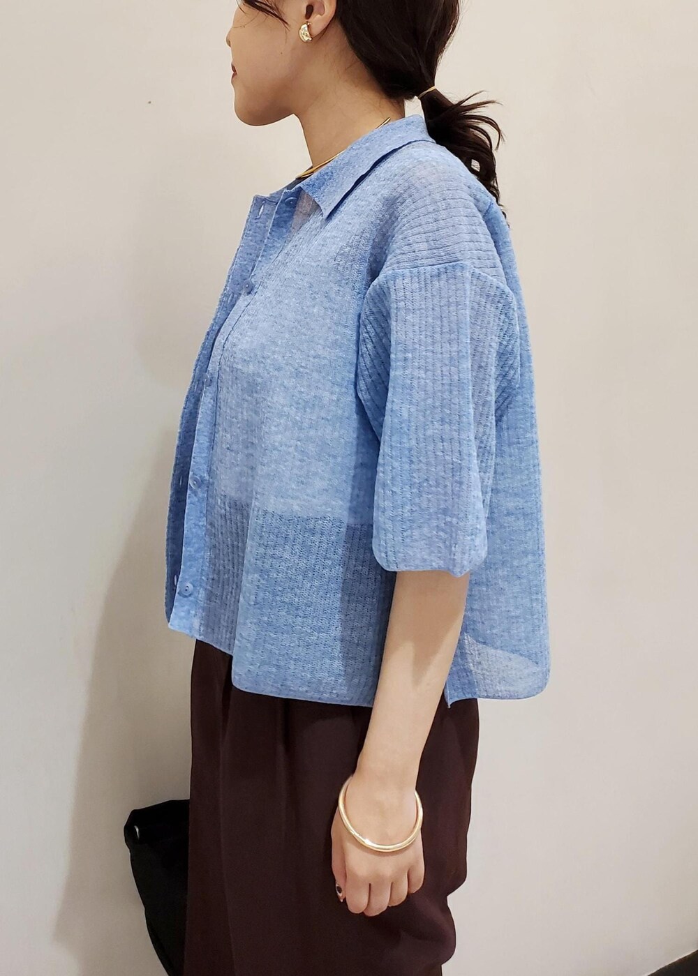 ブラック系のハンドバッグ、ブルー系のカーディガン/ボレロ、ホワイト系のタンクトップを着用したレディースの夏コーディネートの5枚目の写真