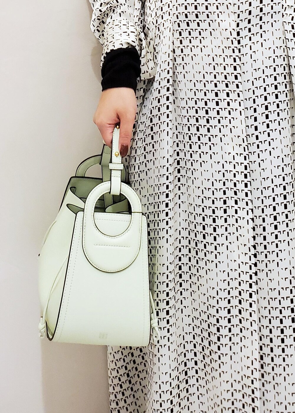 グリーン系のハンドバッグ、ホワイト系のスニーカー、ホワイト系のワンピースを着用したレディースの冬コーディネートの7枚目の写真