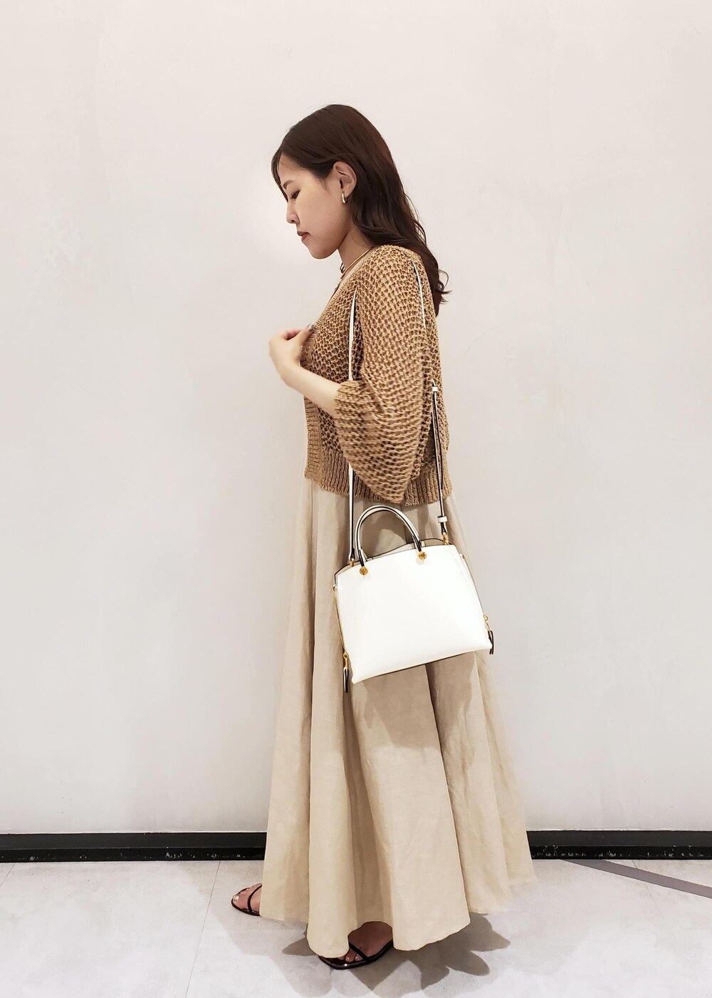 ホワイト系のハンドバッグ、ベージュ系のワンピース、ベージュ系のカーディガン/ボレロを着用したレディースの夏コーディネートの2枚目の写真