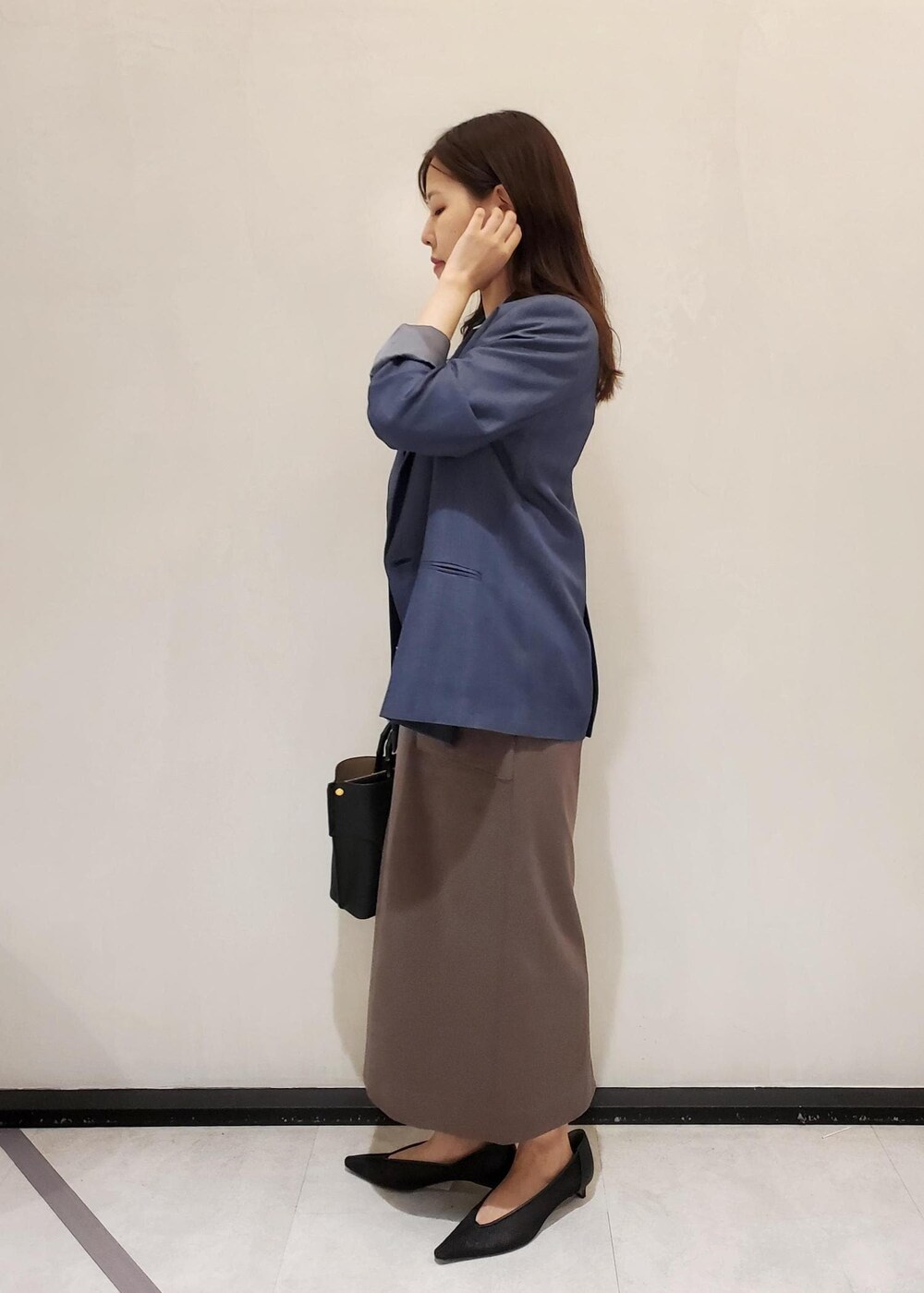 ブラック系のパンプス、ブルー系のテーラードジャケット、ブラック系のハンドバッグを着用したレディースの秋コーディネートの2枚目の写真