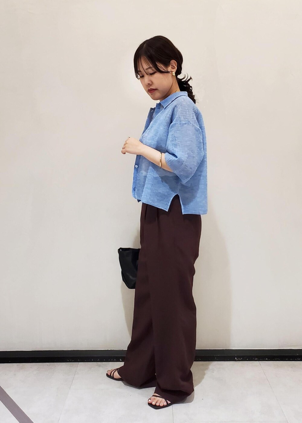 ブラック系のハンドバッグ、ブルー系のカーディガン/ボレロ、ホワイト系のタンクトップを着用したレディースの夏コーディネートの2枚目の写真